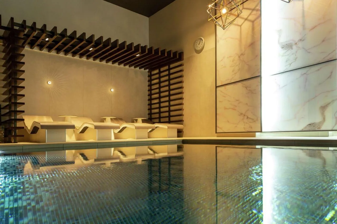 Indoor swimming pool with poolside seating at Hilton Aberdeen TECA